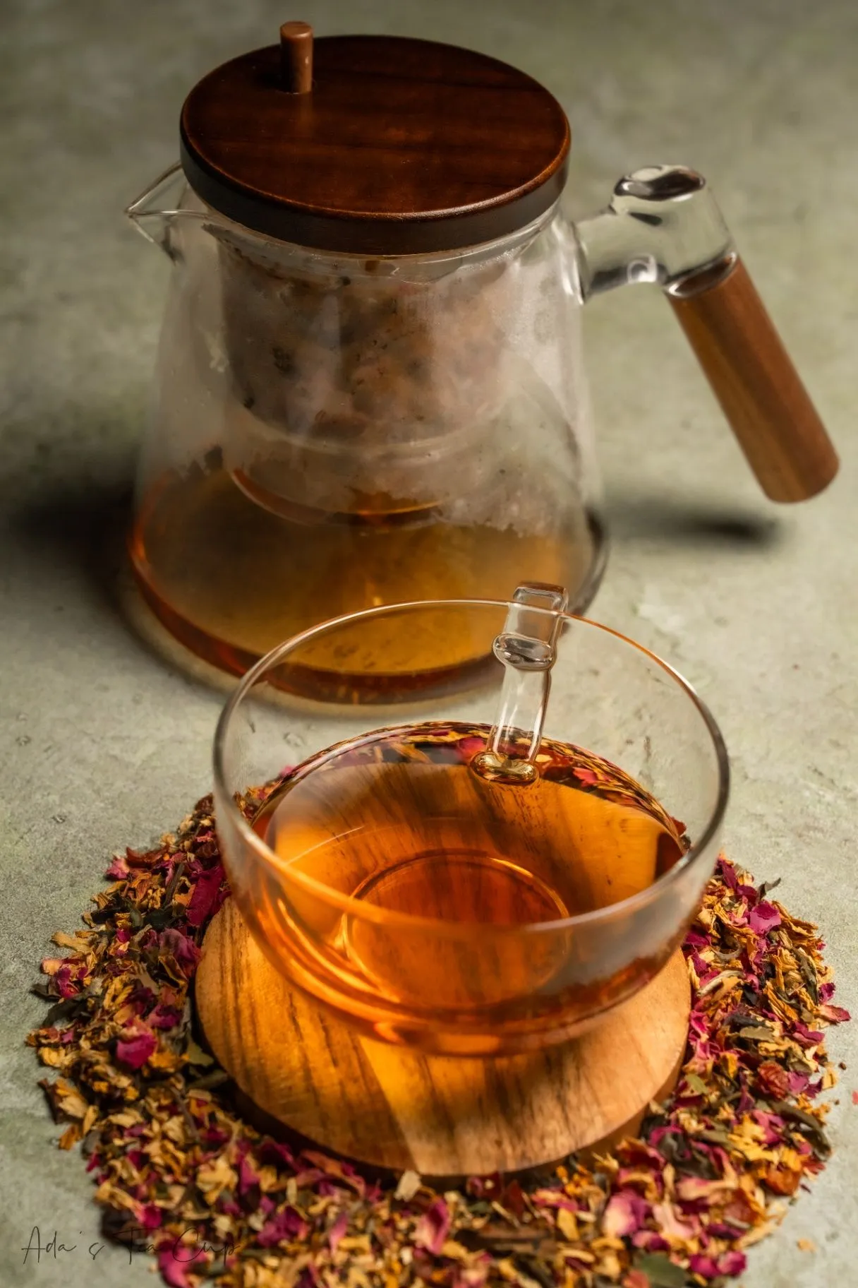 Glass teapot beside a floral tea cup in a peaceful tea setting