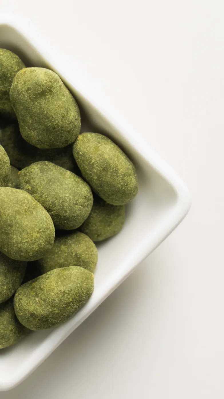 Uji-Matcha covered almonds gathered in a white dish.