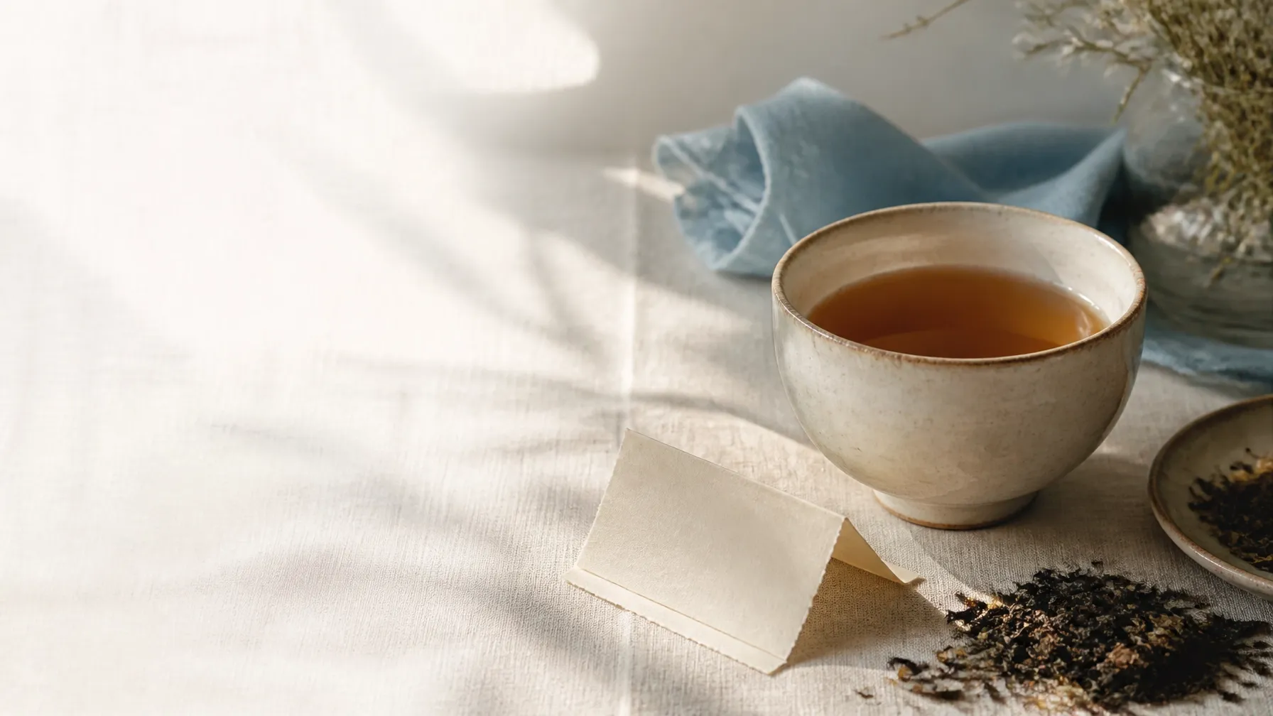 A teacup, loose-leaf tea, note, and blue napkin in soft light